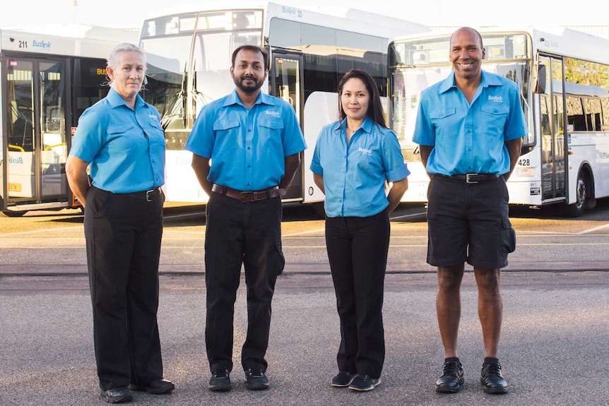 Four local bus drivers standing in front of urban buses