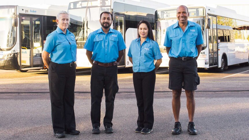 Four local bus drivers standing in front of urban buses