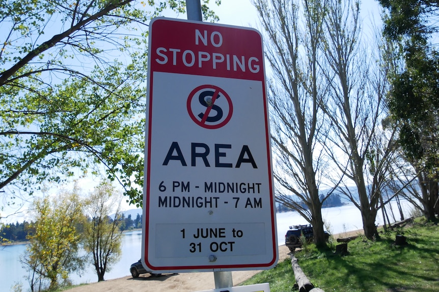 A "no camping" sign in front of a lake.