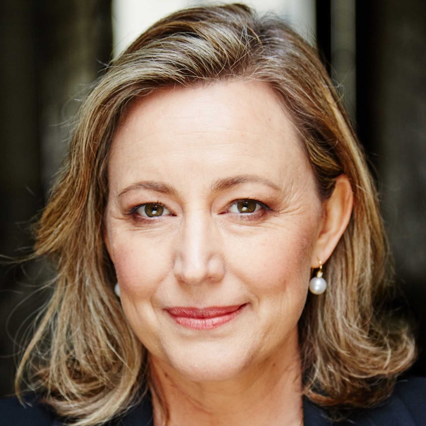 A smiling woman in a black blazer and white shirt