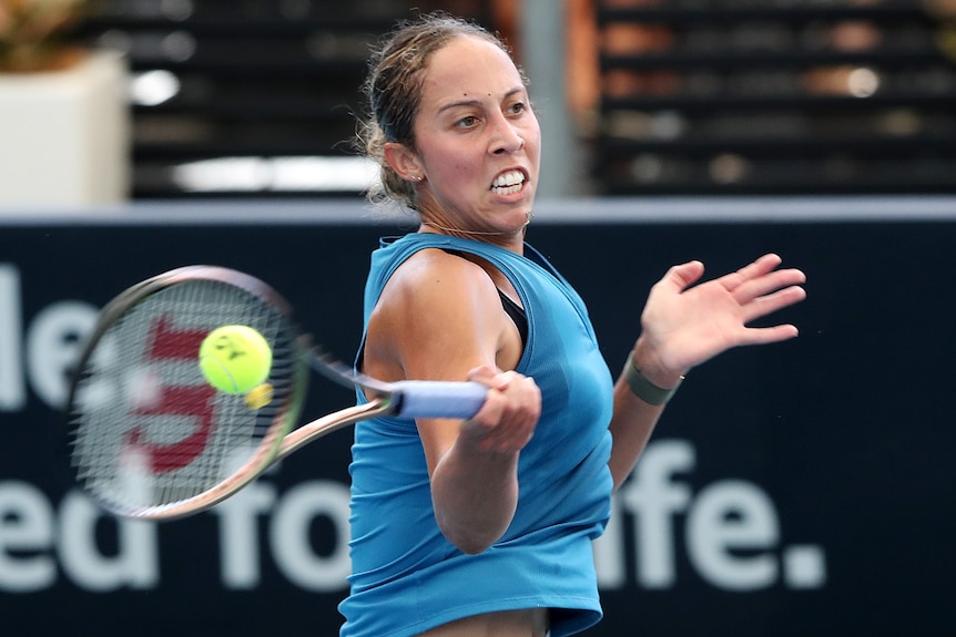 A female American tennis player hits a forehand.