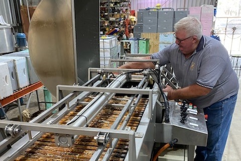 A man working with a machine that extracts honey