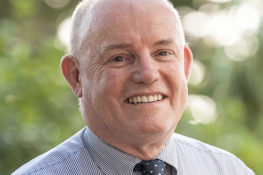 A man in a shirt and tie, smiling