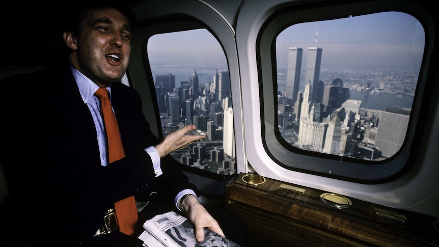 Archival image of Donald Trump in a helicopter, looking out onto the New York skyline (1987).