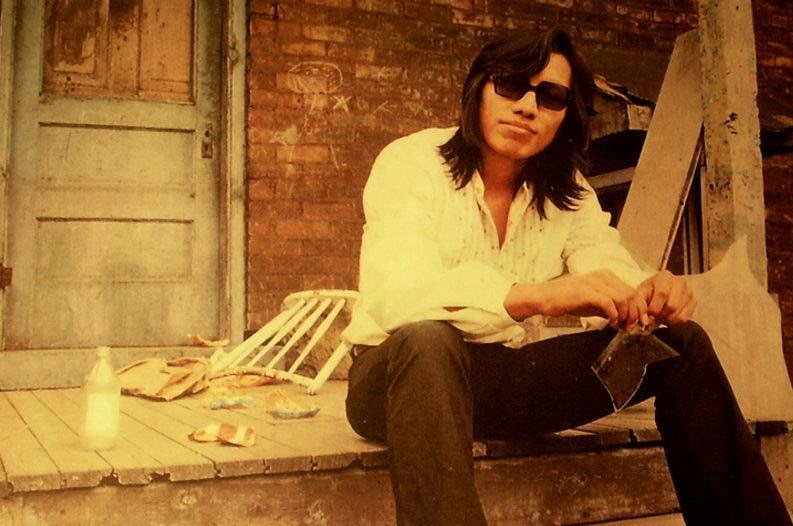 Rodriguez sits on the porch of a house