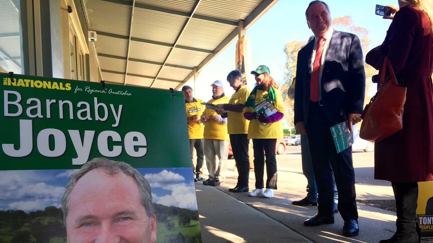 Barnaby Joyce stands with volunteers next to a Nationals sandwich board at a Tamworth pre-polling centre.