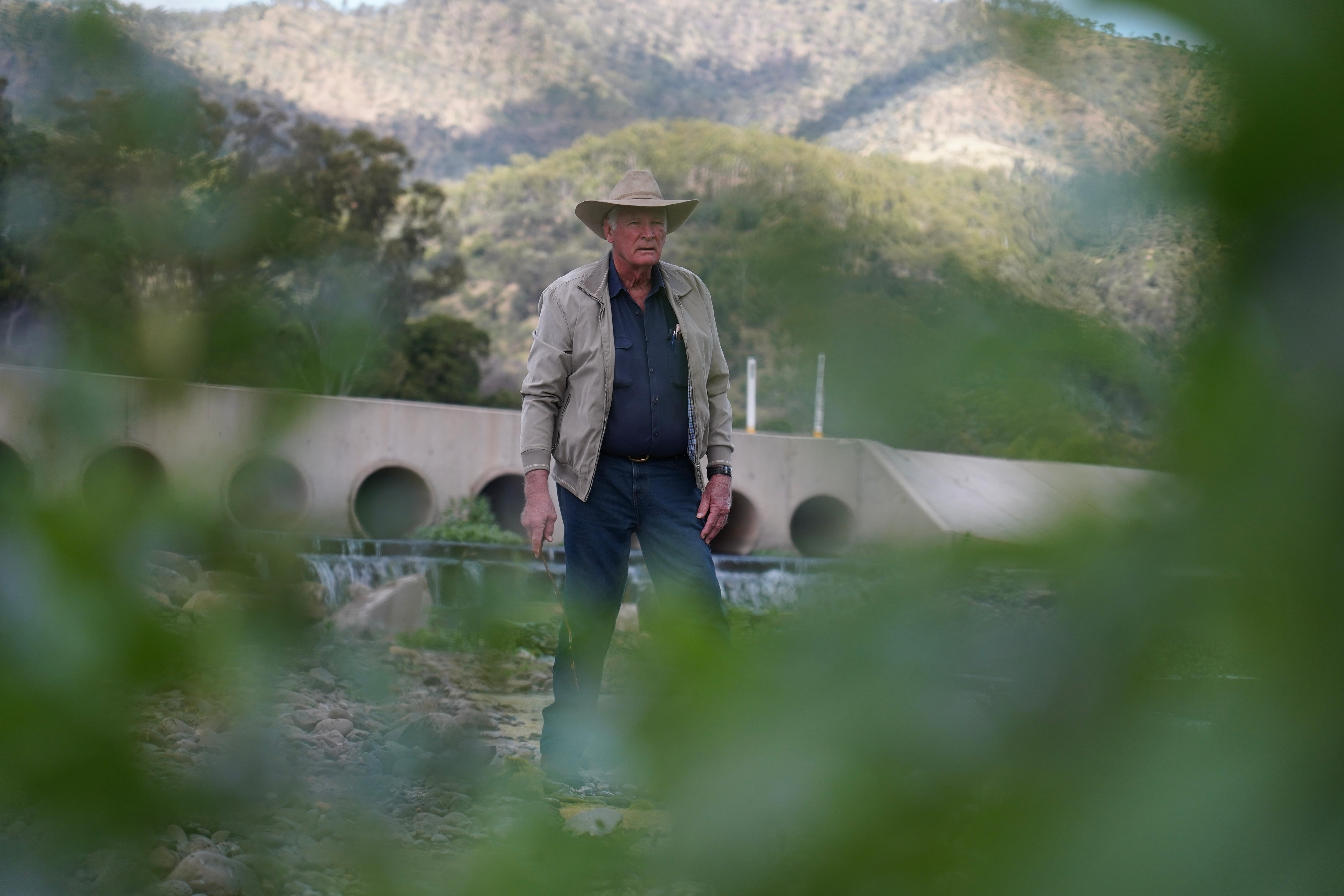 Man standing in front of river with leaves