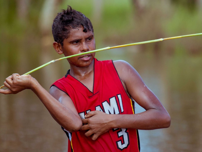 Junior Dirdi holds vegetation, shaped like a spear