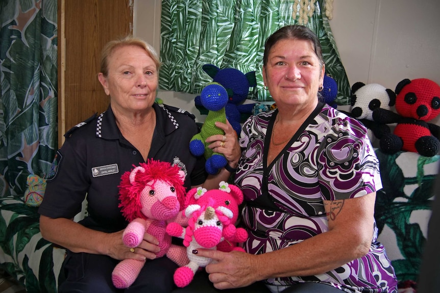 Police officer Dayel Kerley sits next to Maz Gough, both women are holding crocheted animals used as trauma toys