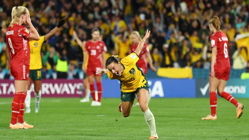 Hayley Raso of the Matildas runs with her arms raised in the air as she celebrates.