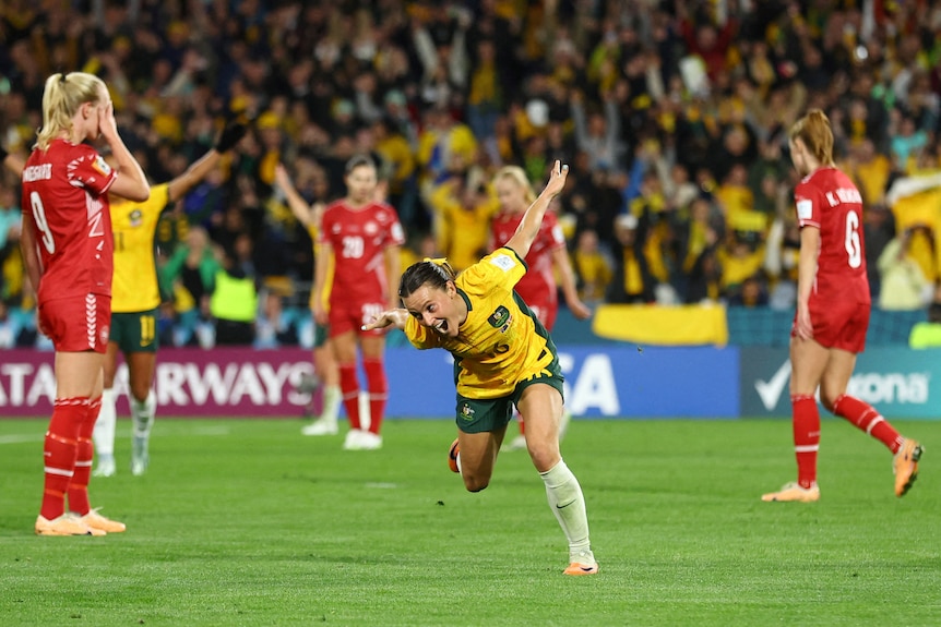 Hayley Raso of the Matildas runs with her arms raised in the air as she celebrates.
