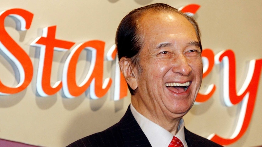 Macao tycoon Stanley Ho laughs in front of a sign that says Stanley.