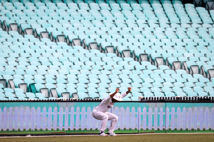 A cricketer stretches in front of empty seats at the SCG