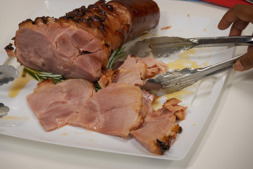 A photo of a Christmas ham which has been sliced and served.