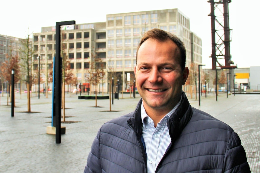 A middle aged man in a puffer jacket smiling at the camera 