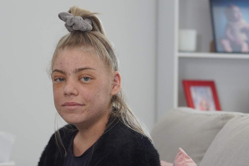 A woman looking at the camera sitting on her couch