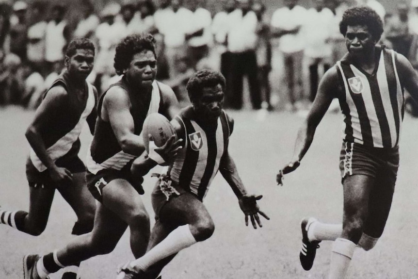 Four players run after the ball during a football match on the Tiwi Islands.