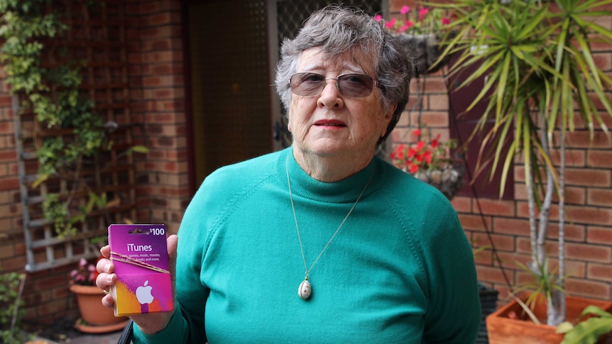 Scam victim Jenni Woodroffe, 80, holds a bundle of iTunes vouchers.