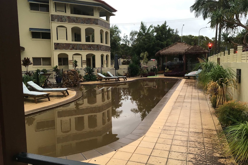 The pool of a unit complex is turned brown from floodwaters.