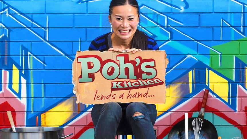 Poh Ling holding a cardboard sign reading 'Poh's Kitchen Lends a Hand'