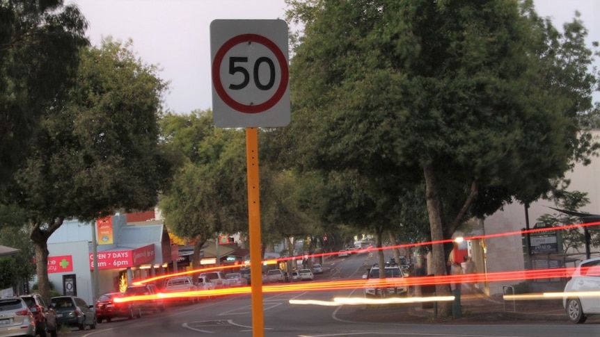 A speed sign, on country street, with a flash of light.