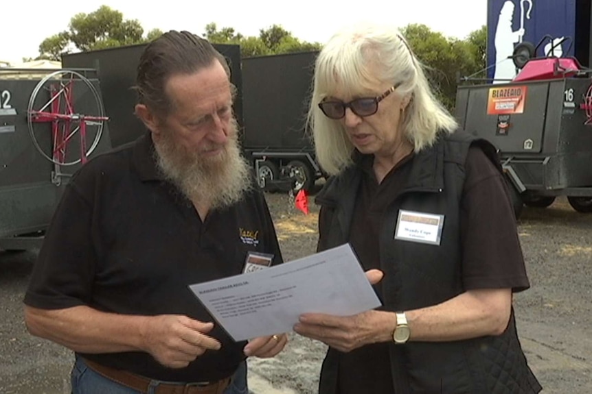 A man and a woman talking among trailers outside.