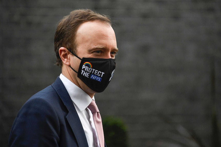 Britain's Health Secretary Matt Hancock walks wearing a mask reading "Protect the NHS".