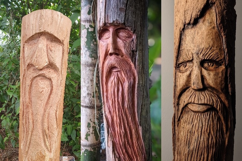 Three logs each with a carved face of a wood spirit