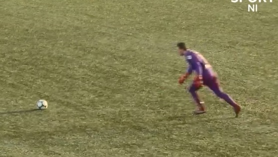 A man wearing purple runs up towards a soccer ball in preparation to kick it