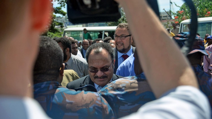 PNG leader Peter O'Neill walks with members of his government to the gates of government house in Port Moresby.
