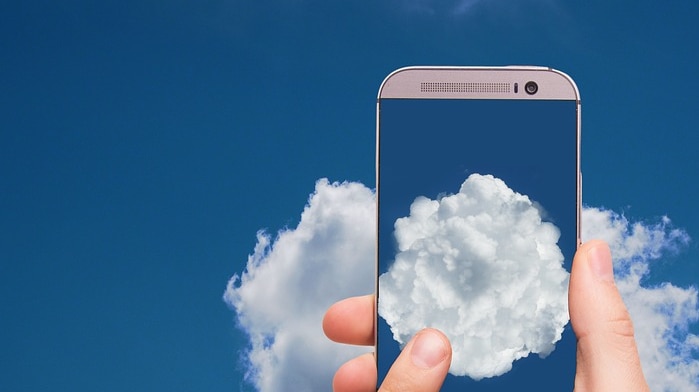 image of mobile phone displaying a cloud set against a sky with clouds
