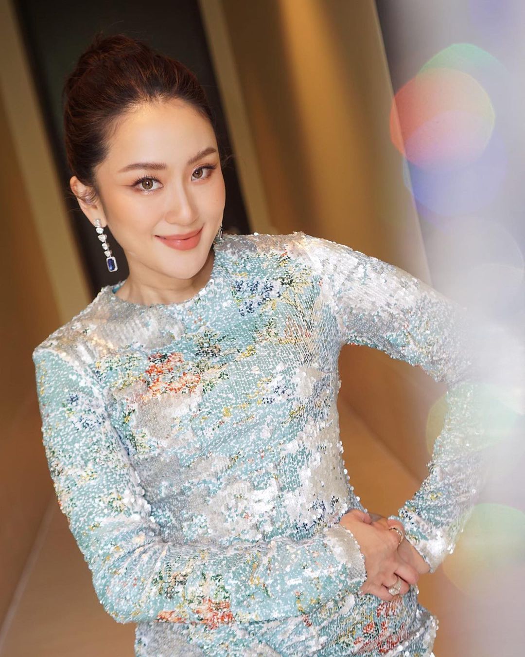 An Asian woman in diamond earrings and a sequined dress
