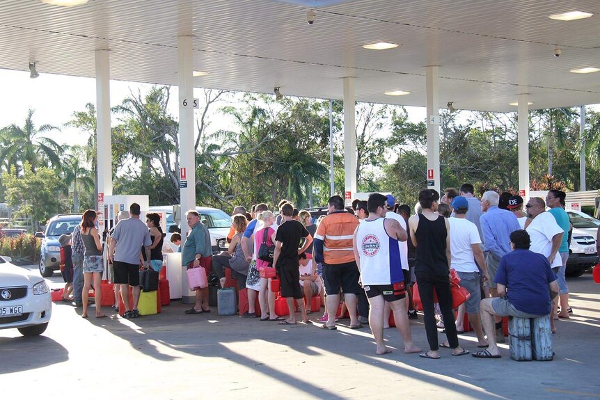 People with their jerry cans queue at a petrol station