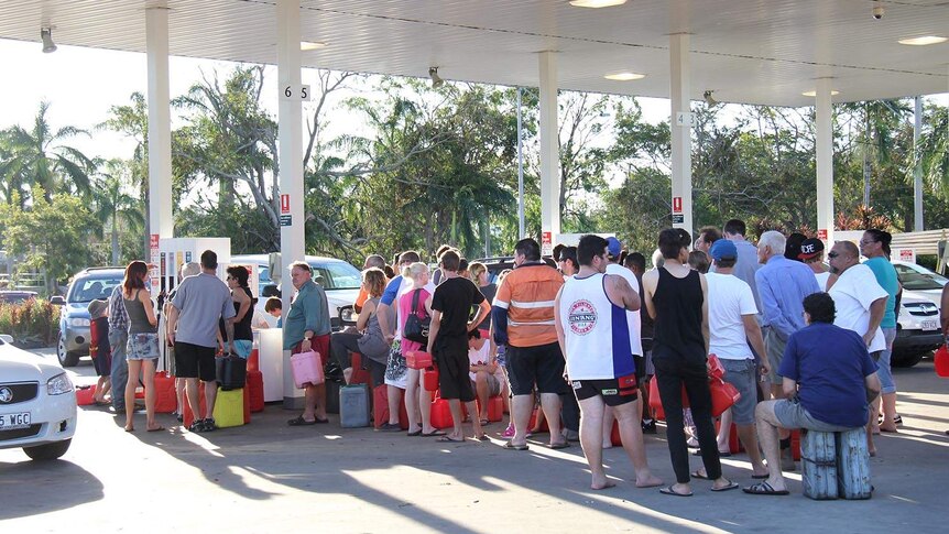 People with their jerry cans queue at a petrol station