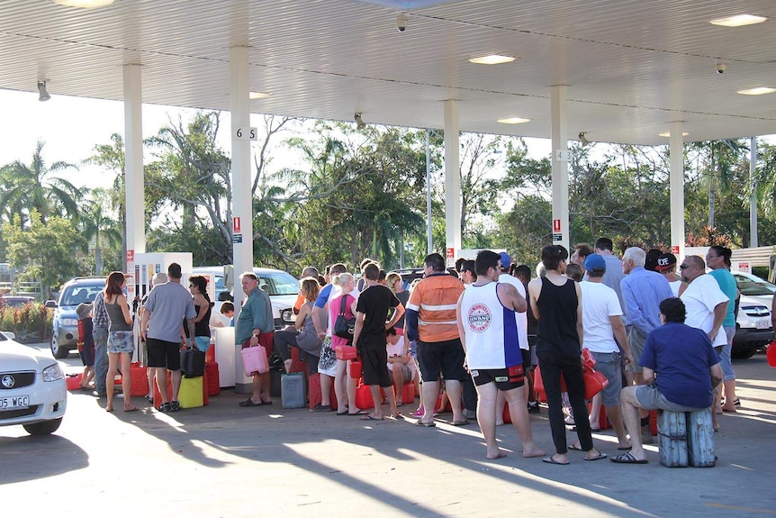 People with their jerry cans queue at a petrol station