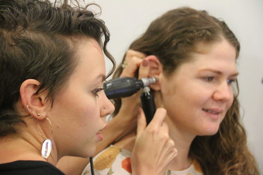 student checks another student ears with instrument