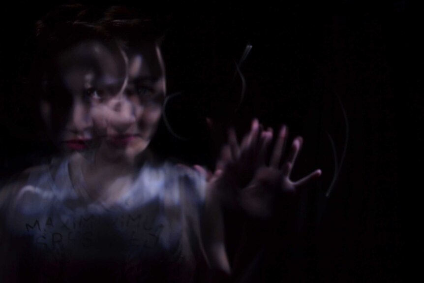 A blurred image of a woman's face with her hand held up to depict the impact of migraine and possible treatments.