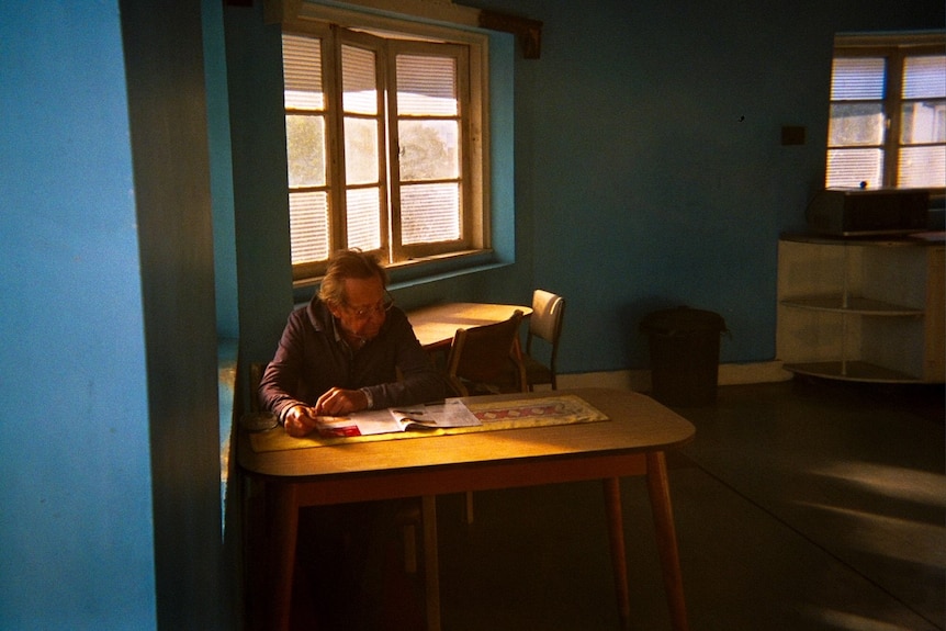 Man sitting at a table reading a magazine.
