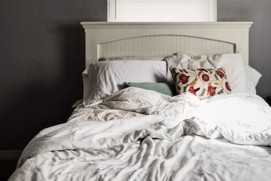 A double bed with white bed linen and a colourful pillow case for a story about how often you should change your sheets.