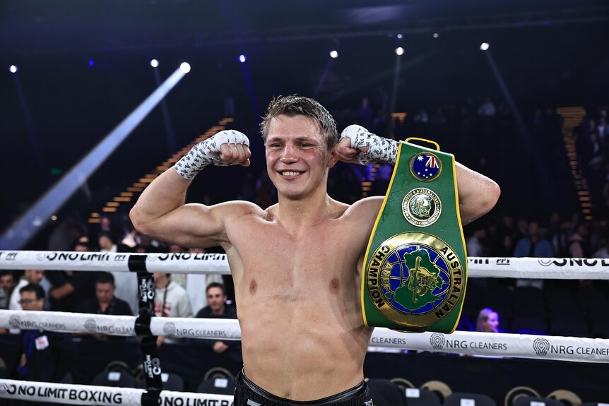 Nikita Tszyu flexes his muscles after a fight, with an Australian Champion belt draped over his left arm.