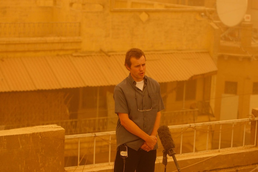 Dean Yates doing a piece to camera during a sandstorm in Baghdad.