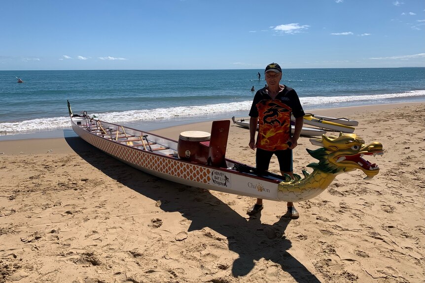 Vlad Chudoschnik stands next to a dragon boat at the beach