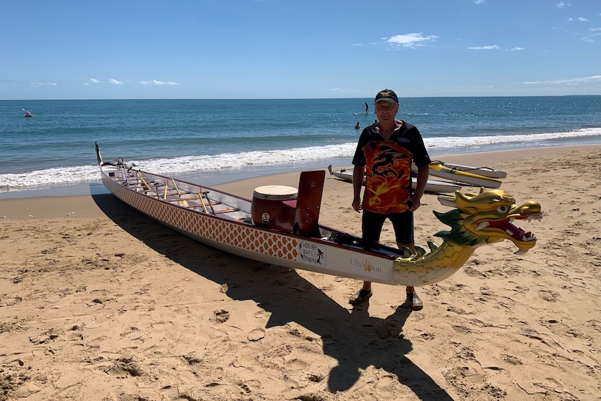 Vlad Chudoschnik stands next to a dragon boat at the beach