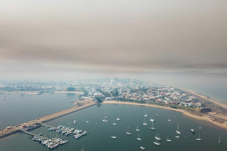 Drone shot of smoke polluting a city and harbour