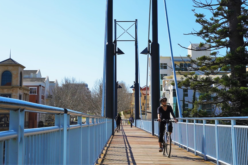 A woman rides her bike over bridge in East Perth