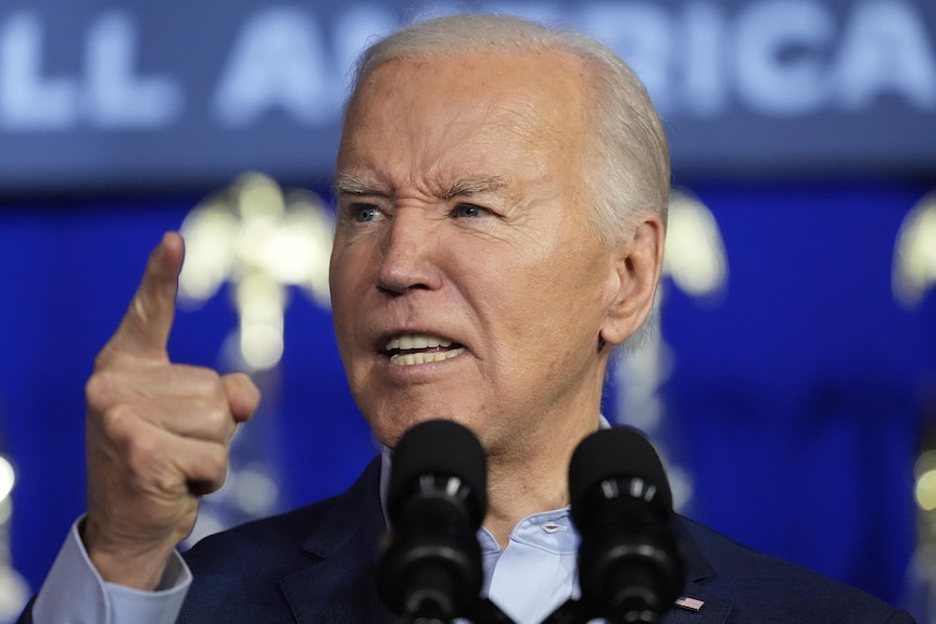 Joe Biden speaks into a microphone, looking angry and pointing a finger