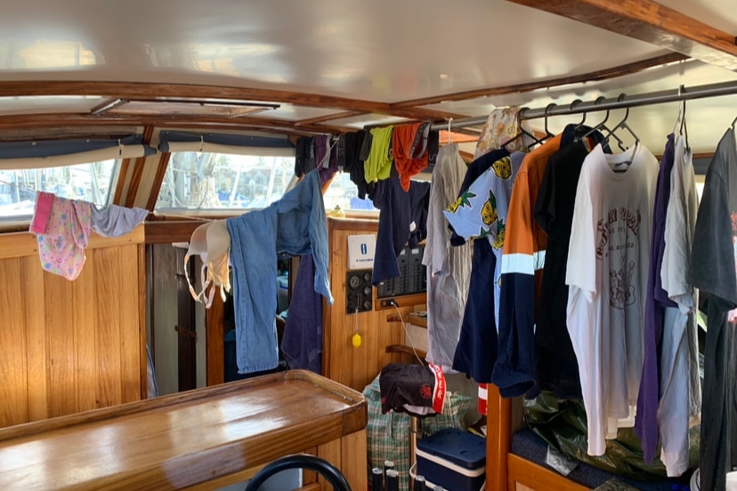 Clothes hanging on coat hangers inside a boat.