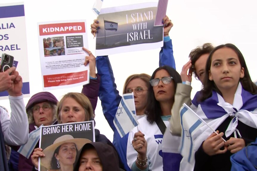 Women holding placards in support of Israel and girl wrapped in the Israeli flag
