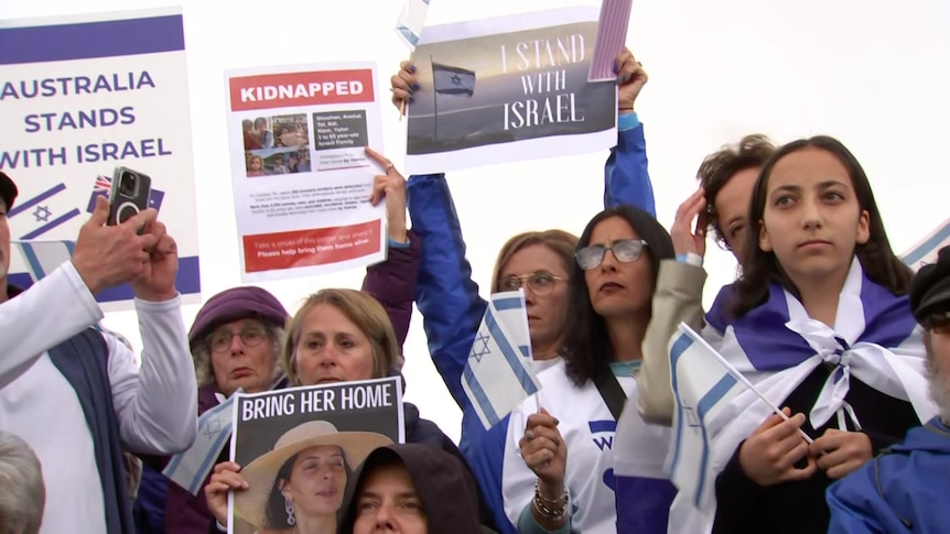 Women holding placards in support of Israel and girl wrapped in the Israeli flag