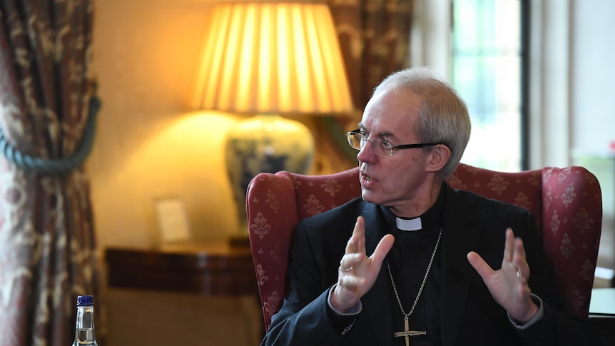 justin welby gesturing with hands on red seat